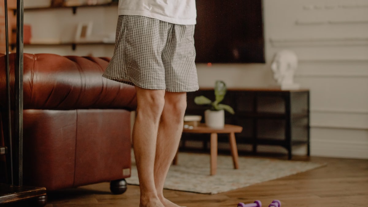 Man practicing balance exercise at home with a focus on legs and barefoot posture.